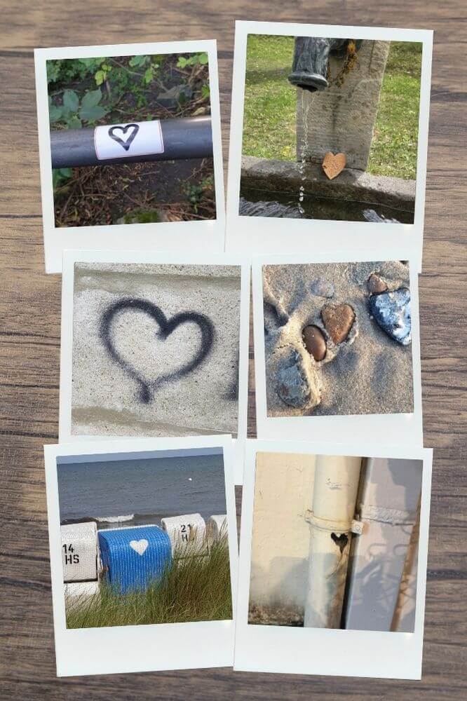 Sechs Polaroid-Fotos liegen leicht versetzt auf einem Untergrund in Holzoptik. Die Motive zeigen verschiedene Herzen, darunter ein Graffiti auf Beton, Steine im Sand, ein blaues Herz auf einem Strandkorb und ein Herz aus Rinde an einem Steinbrunnen.